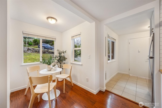 dining area featuring wood finished floors, a healthy amount of sunlight, and baseboards