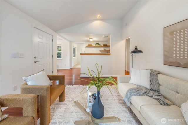 living area featuring baseboards, lofted ceiling, and wood finished floors