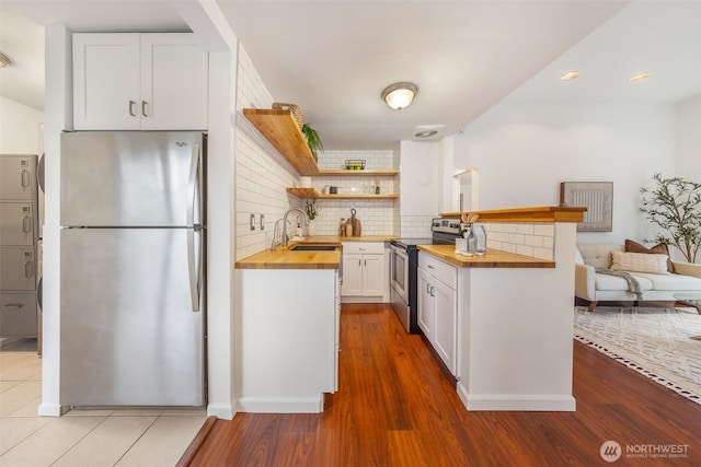 kitchen featuring a sink, white cabinetry, stainless steel appliances, decorative backsplash, and wooden counters