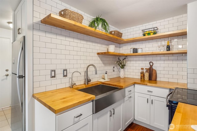 kitchen featuring butcher block countertops, open shelves, and a sink