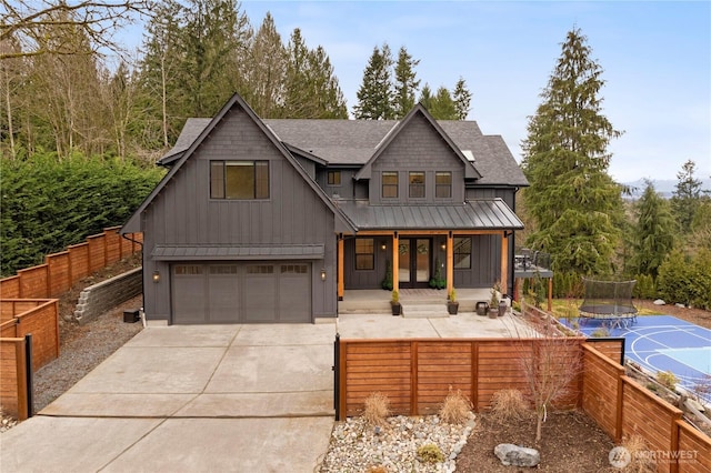 view of front of house featuring fence, french doors, a garage, a trampoline, and board and batten siding