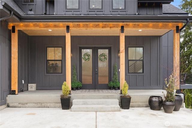 property entrance featuring covered porch, board and batten siding, a shingled roof, and french doors