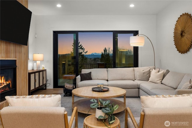 living room with a glass covered fireplace, recessed lighting, and wood finished floors