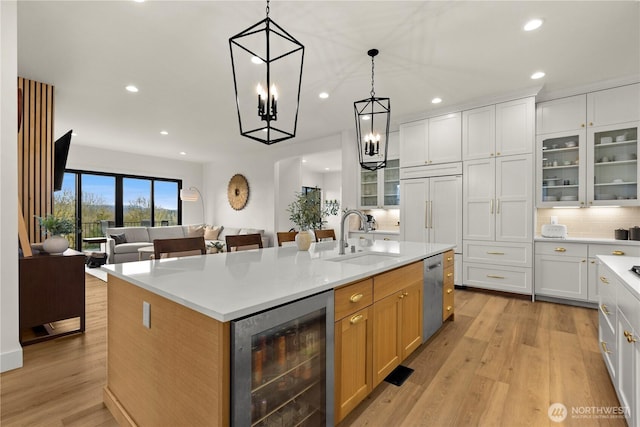 kitchen featuring a kitchen island with sink, a sink, wine cooler, light wood-style floors, and dishwasher