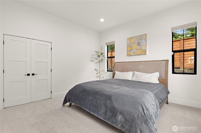 bedroom featuring multiple windows, light colored carpet, and baseboards