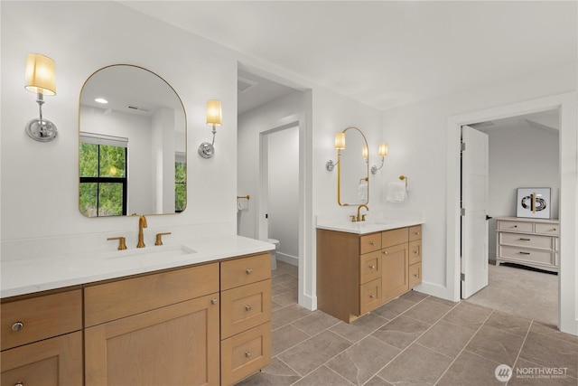 full bathroom with tile patterned floors, toilet, two vanities, and a sink