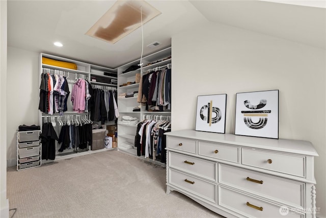 spacious closet featuring visible vents, light colored carpet, attic access, and vaulted ceiling