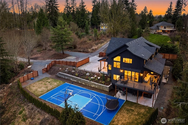 view of sport court featuring a lawn, basketball hoop, and fence