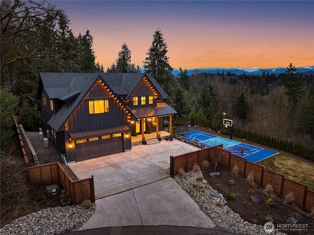 view of swimming pool with shuffleboard, fence, and a forest view