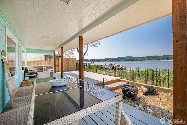 wooden terrace featuring an outdoor living space with a fire pit, fence, and a water view