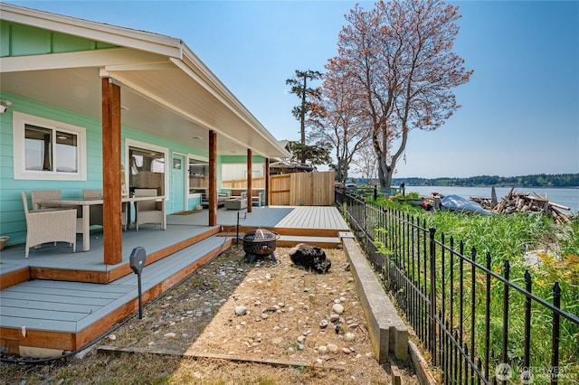 wooden deck featuring a fenced backyard, a water view, and an outdoor fire pit