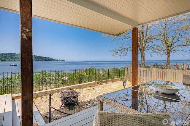 view of patio with outdoor dining area, a water view, a fenced backyard, and an outdoor fire pit