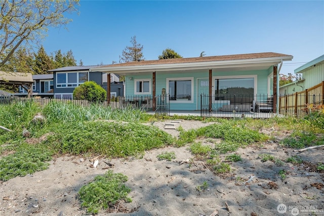 rear view of house featuring a porch and fence