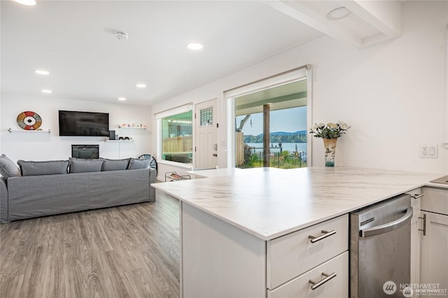 kitchen with light wood finished floors, a peninsula, light countertops, white cabinets, and dishwasher