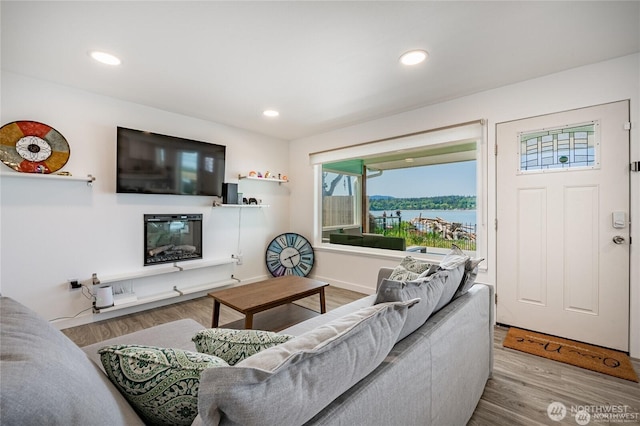 living room with a glass covered fireplace, recessed lighting, wood finished floors, and baseboards