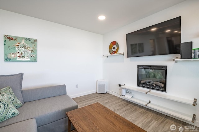 living room with a glass covered fireplace, recessed lighting, baseboards, and wood finished floors