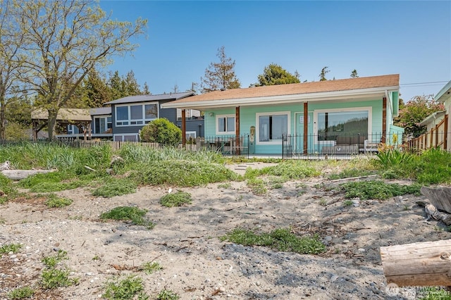 rear view of property featuring covered porch and fence