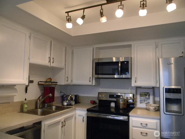 kitchen featuring white cabinets, appliances with stainless steel finishes, a raised ceiling, and a sink