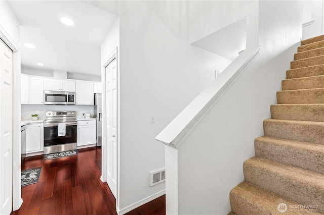 stairway with visible vents, recessed lighting, and wood finished floors