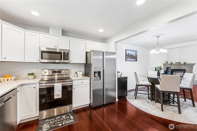 kitchen featuring recessed lighting, stainless steel appliances, white cabinets, dark wood-style flooring, and hanging light fixtures