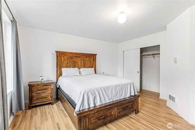 bedroom featuring a closet, visible vents, light wood-style flooring, and baseboards