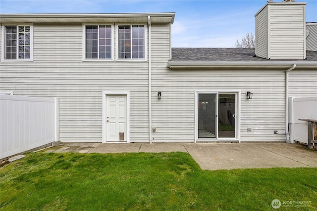 back of house featuring a patio, a lawn, fence, and a chimney