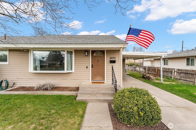 view of front of property with a front lawn, fence, and a shingled roof