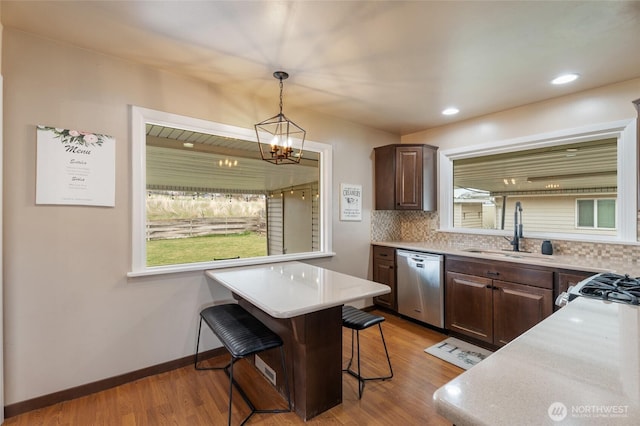 kitchen with a sink, a kitchen breakfast bar, tasteful backsplash, stainless steel appliances, and light wood-style floors