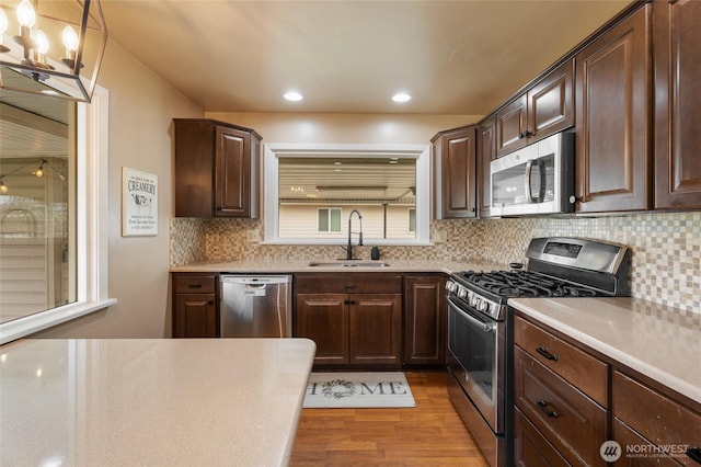 kitchen featuring a sink, light countertops, light wood finished floors, and stainless steel appliances