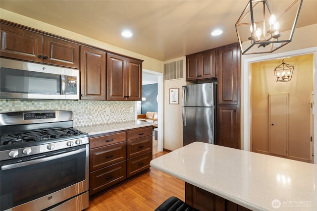 kitchen with visible vents, dark brown cabinetry, appliances with stainless steel finishes, and light wood-style flooring