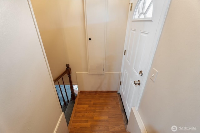 corridor with an upstairs landing and wood finished floors