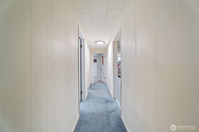 hallway with carpet flooring and wood walls