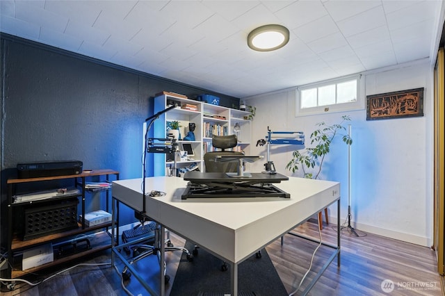 office space featuring a textured wall, baseboards, and wood finished floors