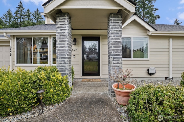 view of exterior entry featuring a shingled roof