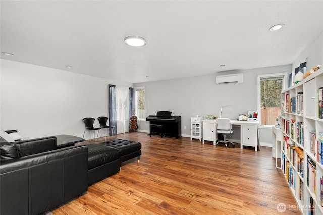 living area with a wall mounted air conditioner, baseboards, light wood-style flooring, and recessed lighting