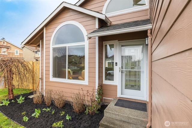 entrance to property featuring fence and a shingled roof