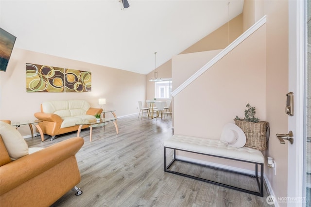 living room with high vaulted ceiling, baseboards, and wood finished floors