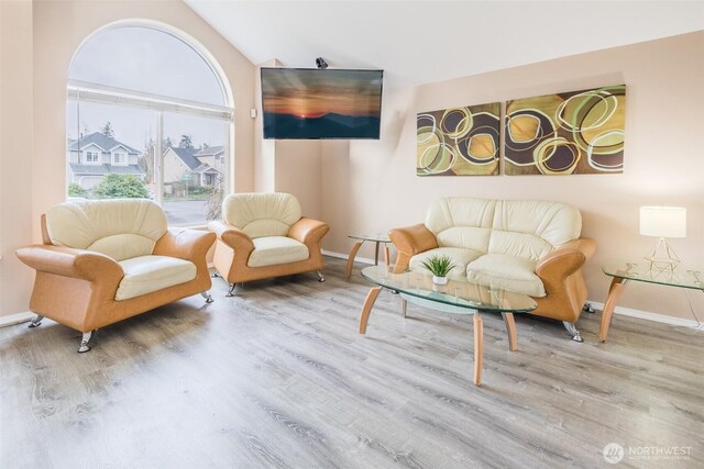 living room with lofted ceiling, wood finished floors, and baseboards