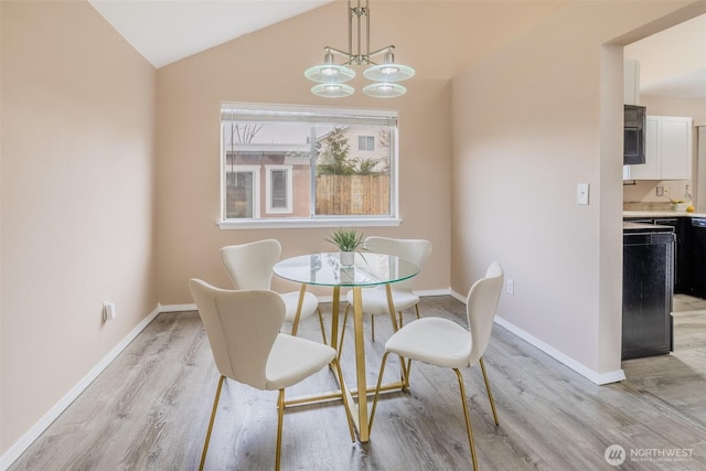 dining room featuring baseboards, a notable chandelier, light wood-style flooring, and vaulted ceiling