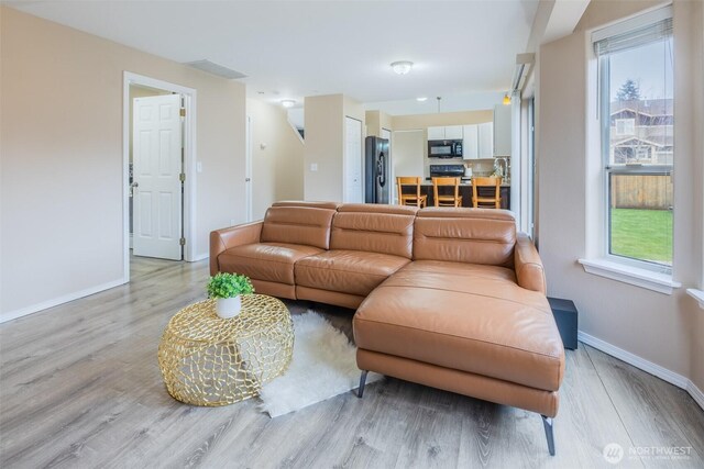 living room with baseboards, plenty of natural light, and light wood-style floors