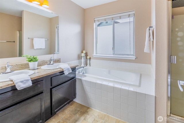 bathroom with double vanity, a shower stall, a garden tub, and a sink