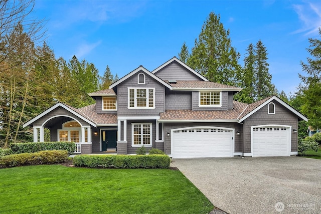 view of front of house with a front lawn, a garage, covered porch, and aphalt driveway