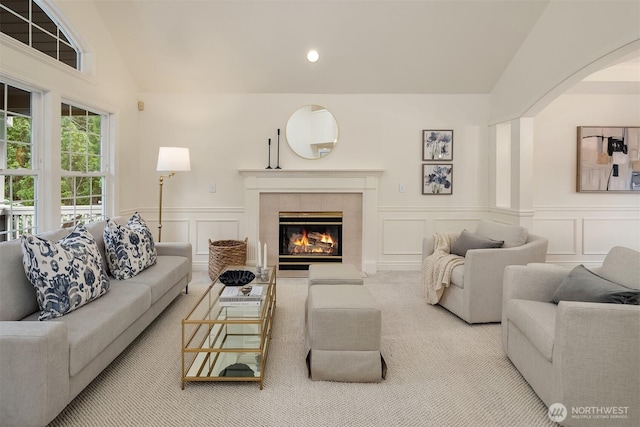 carpeted living room featuring recessed lighting, vaulted ceiling, a tiled fireplace, and a decorative wall