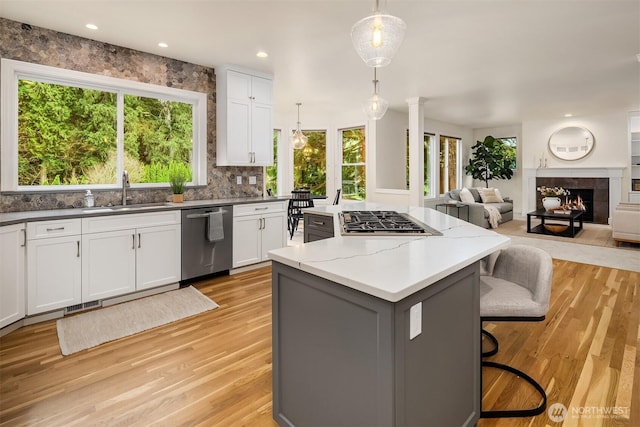 kitchen with a kitchen island, open floor plan, white cabinets, stainless steel appliances, and a sink