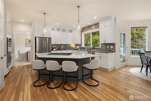 kitchen with a breakfast bar area, backsplash, light wood-style flooring, and appliances with stainless steel finishes