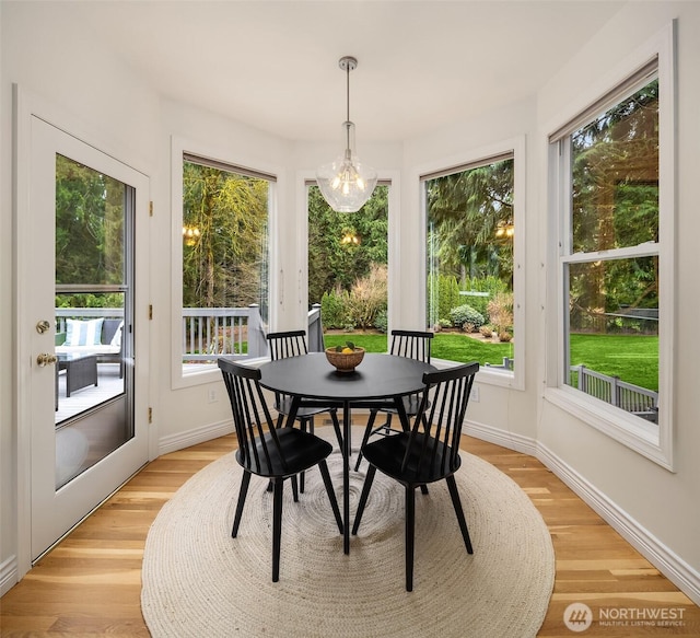 dining area featuring a wealth of natural light, a notable chandelier, baseboards, and light wood-style floors