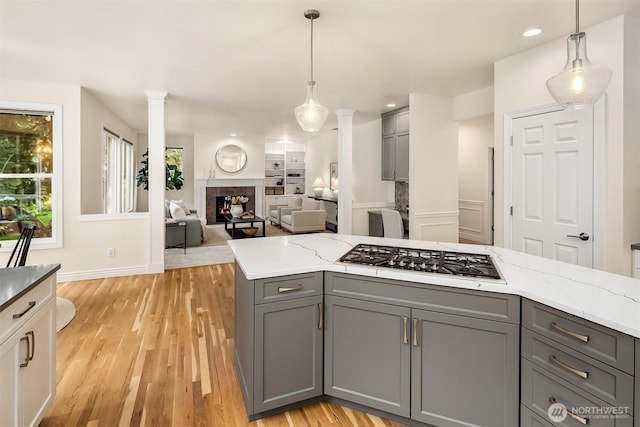 kitchen with stainless steel gas cooktop, gray cabinets, a fireplace, and light wood-style floors