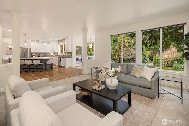 living area with recessed lighting, light wood-style flooring, baseboards, and ornate columns