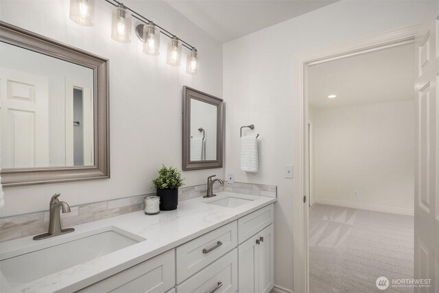 full bath with double vanity, baseboards, and a sink