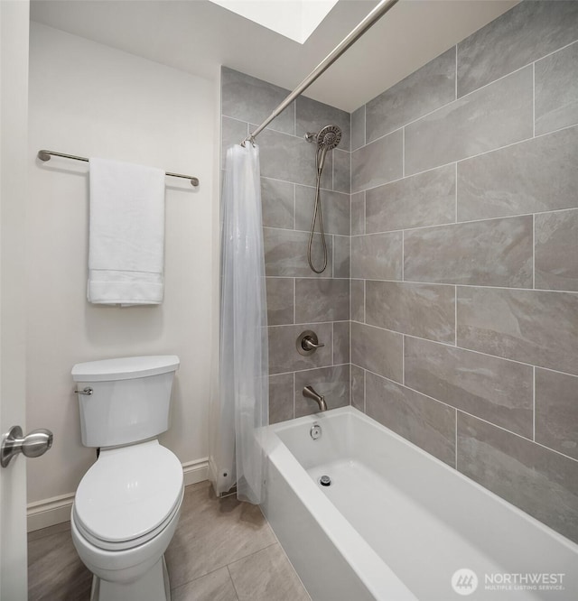 full bath featuring a skylight, toilet, baseboards, and shower / tub combo